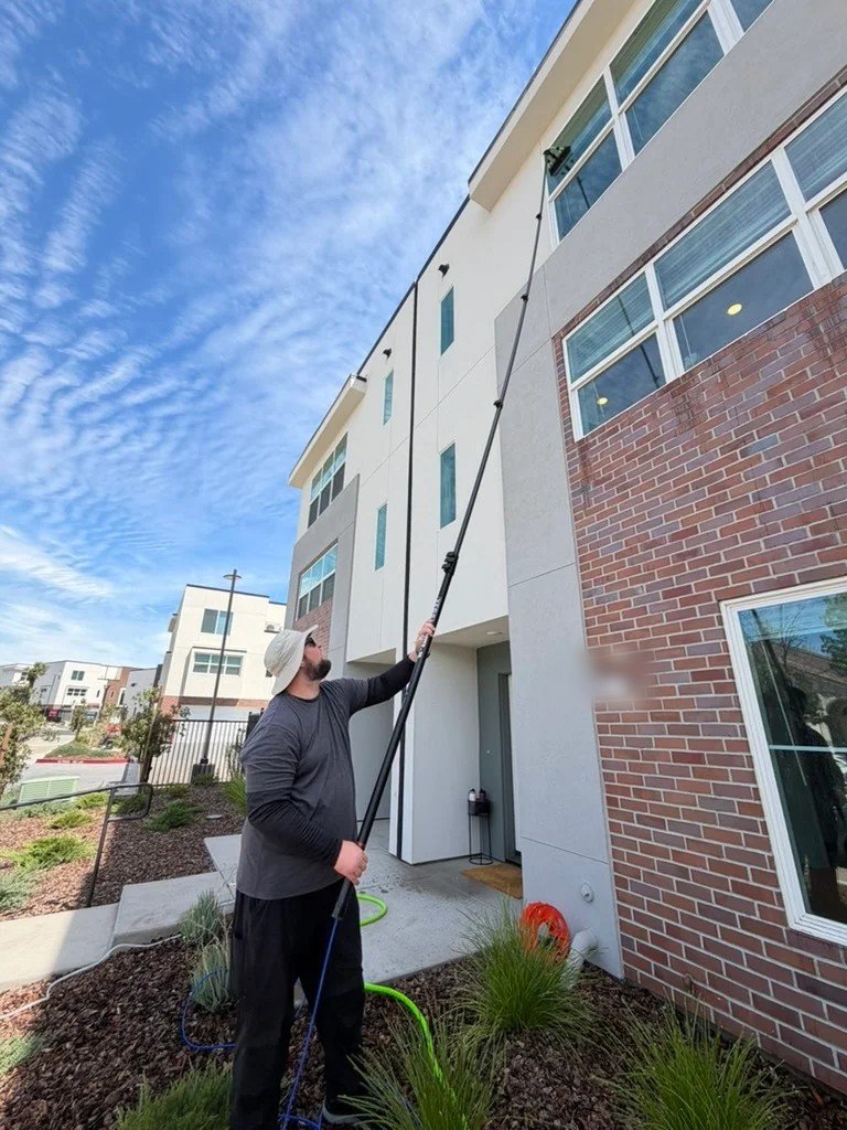 Alex of Radiant Window Care cleaning third story windows with a water fed pole