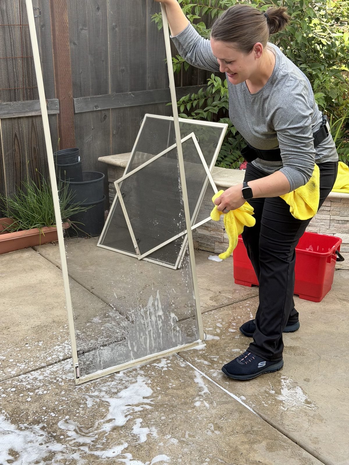 Window screens being washed on site in the driveway